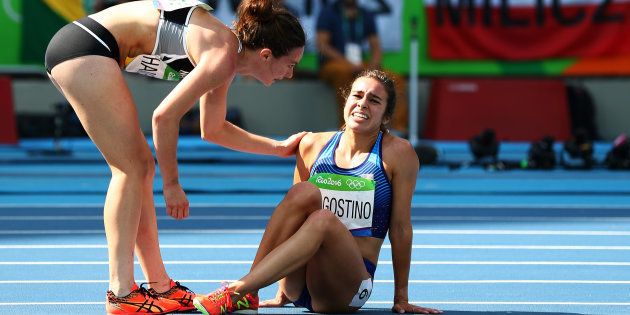 Abbey D'Agostino of the United States (R) is assisted by Nikki Hamblin of New Zealand after a collision during the Women's 5000m Round 1.
