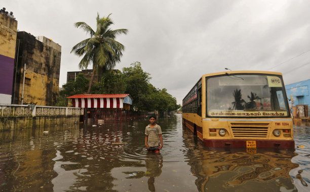 A boy wades next to a partially submerged bus in a flooded locality in Chennai, India, December 5, 2015. REUTERS/Anindito Mukherjee