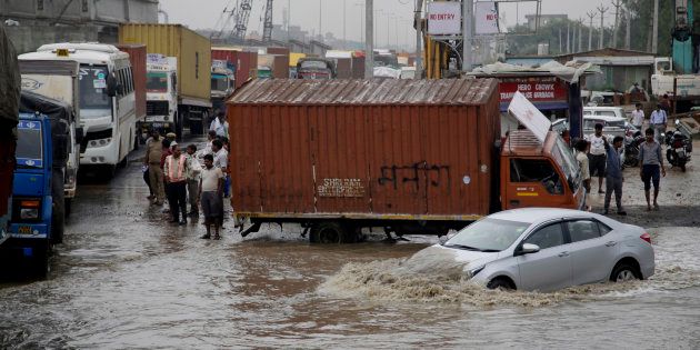 A car navigates its way through a flooded street after heavy rainfall.