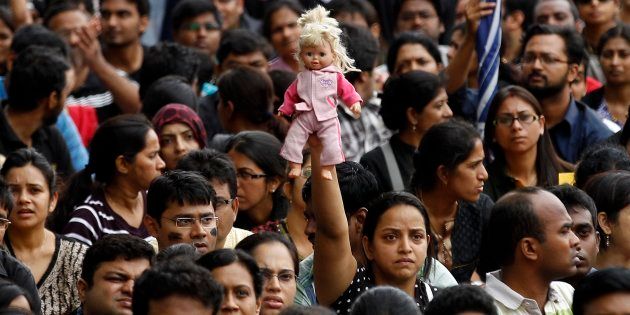 A parent holds high a doll belonging to her child as she participates in a protest against alleged police inaction after a six-year-old was raped at a school, in Bangalore, India, Saturday, July 19, 2014.