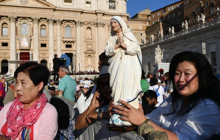 A faithful holds a statue of Mother Teresa.