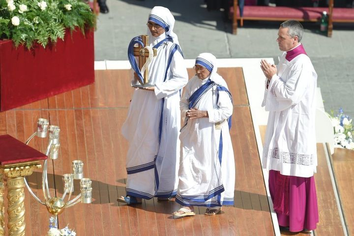 Nuns of the Missionary of Charity carry the mother's relics as a religious man prays during a holy mass for her canonisation.