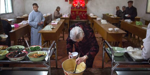 SHA COUNTY, CHINA - MARCH 18: An elderly Chinese resident serves herself food during lunch at the Ji Xiang Temple and nursing home on March 18, 2016 in Sha County, Fujian province, China. The Buddhist temple, which houses a nursing home, opened in 2000 as a spiritual promise by a revered elderly monk to provide care and compassion for the aged. Local officials say it is the only temple in China that provides sanctuary at no cost to its elderly residents, who, in some cases have no family to care for them as their children have migrated to major cities for work. China's rapidly ageing population poses a demographic challenge for the state, as the number of people over age 60 is expected to reach nearly half a billion within 30 years. (Photo by Kevin Frayer/Getty Images)