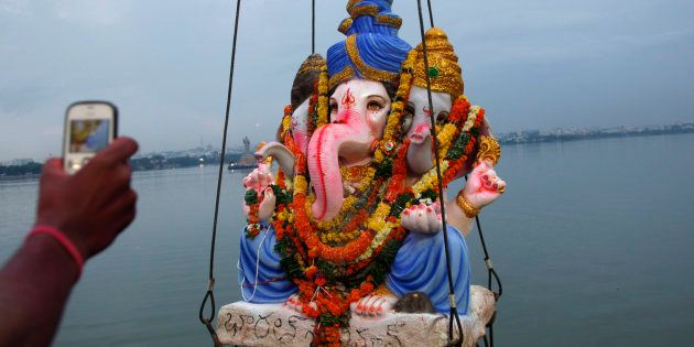A devotee takes a picture of Hindu god Ganesha as it is lifted to be immersed in the Hussain Sagar Lake during Ganesh Chaturthi festival celebrations.