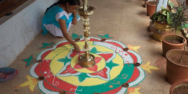 Woman making rangoli during Onam Festival, Kerala, India.