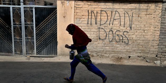 A girl runs with a milk pot through a deserted street in Srinagar as the city remains under curfew following weeks of violence in Kashmir.