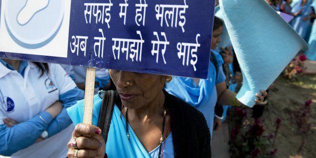 An Indian woman holds a sign reading 'The good only lies in cleanliness, you must understand now my brother'.