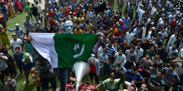 A masked Kashmiri mourner holds up a Pakistani flag in Budgam district on August 16, 2016.