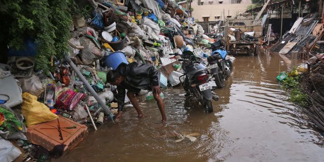 A scrap dealer arranges his collection after rainwater flooded his yard, on the outskirts of Hyderabad.