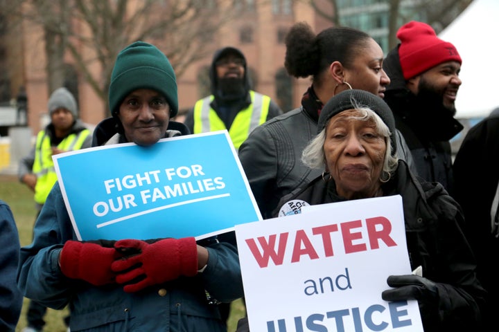 One of the protesters holds a sign reading "WATER and JUSTICE," a reference to the ongoing Flint water crisis.