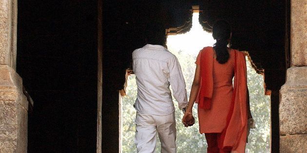 A young Indian couple hold each other's hand as they visit a monument in a park on Valentine's Day.