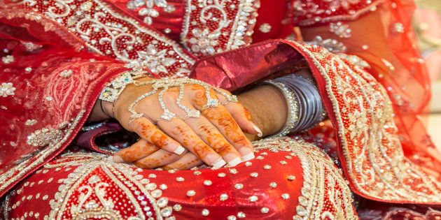 Asian bride rests henna tattoo hands on her wedding dress