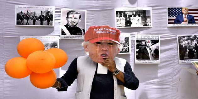 Member of Hindu Sena puts mask of US President Donald Trump as they celebrate his birthday on June 14, 2017 in New Delhi.