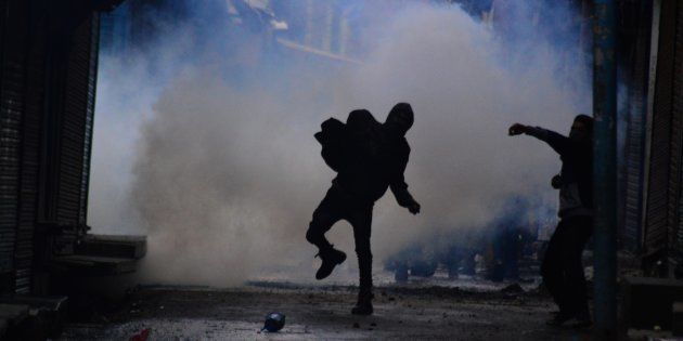 File photo of a boy pelting stones at police personnel amidst heavy tear gas smoke.