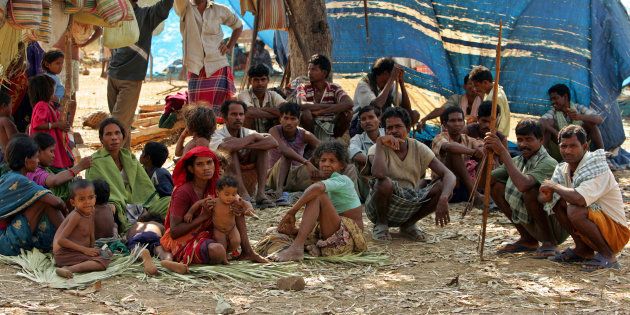 A group of Indian tribe sit in open at a camp in Dornapal in Chhattisgarh, India March 8, 2006. More than 45,000 people have left their homes to live in camps run by the Salwa Judum, but have just bows and arrows to defend themselves against the rebels' guns and explosives. Picture taken March 8, 2006. REUTERS/Kamal Kishore