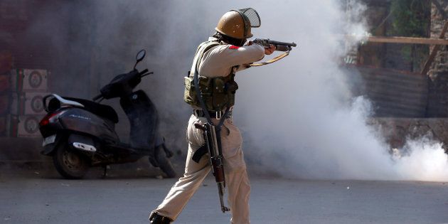 A policeman aims a tear gas gun towards demonstrators during a protest in Srinagar.