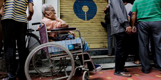 A physically disabled man on a wheel chair waits in queue to exchange or deposit discontinued currency notes outside a bank in Kolkata, India, Thursday, Nov. 10, 2016. As banks reopened after Indian Prime Minister Narendra Modi discontinued Indian currency notes in the denominations of 500 and 1000, banks in all localities were overwhelmed with large queues off people waiting to either deposit or withdraw money from their accounts. (AP Photo/Bikas Das)