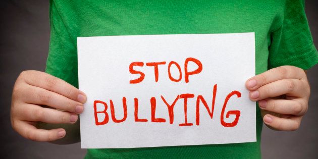 A young boy holds Stop bullying sign.