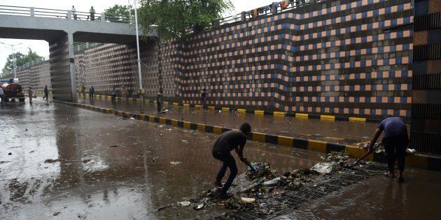 REPRESENTATIVE IMAGE: Indian workers clear blocked drains following heavy rain and flooding in Ahmedabad on July 3, 2017.