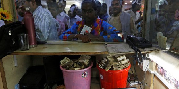 Old high denomination bank notes are seen kept in buckets at a counter as people stand in a queue to deposit their money inside a bank in the northern city of Kanpur, India, November 10, 2016. REUTERS/Adnan Abidi