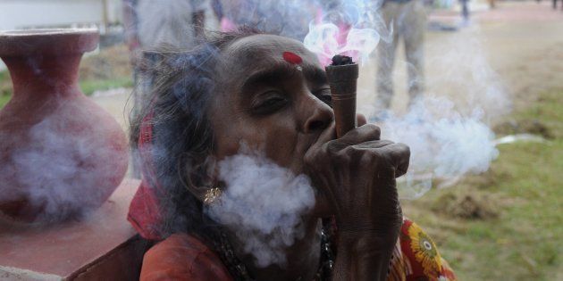 An Indian holy woman smokes marijuana on the eve of the traditional Kharchi Puja festival at Agartala.