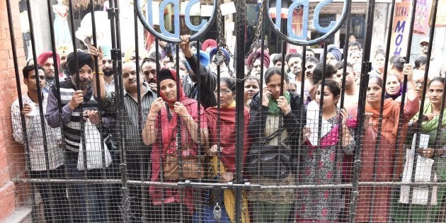 AMRITSAR, INDIA - NOVEMBER 17: Bank customers waiting to withdraw and deposit Indian currency notes outside State Bank Of India at town hall on November 17, 2016 in Amritsar, India. The Reserve Bank asked people not to hoard currency as there is sufficient supply of notes, even as banks struggled to manage the rush of people thronging branches across the country to exchange the scrapped high denomination 1,000 and 500 rupee notes. (Photo by Gurpreet Singh/Hindustan Times via Getty Images)