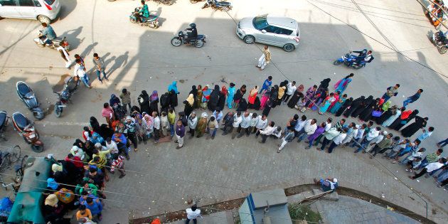 People queue to deposit or exchange their old high denomination banknotes outside a bank.