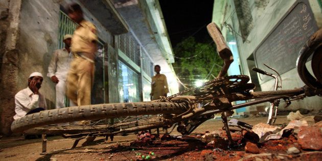 [FILE PHOTO] People walk past a damaged bicycle lying at a blast site inside a mosque in Malegaon on September 9, 2006.