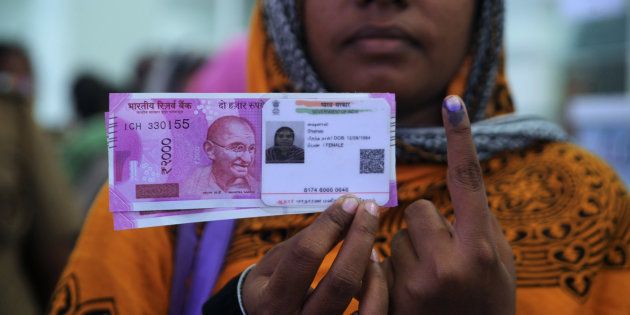 Woman poses with new ₹2,000 notes, her Aadhaar ID card and a finger inked with indelible ink after exchanging withdrawn ₹500 and ₹1,000 banknotes.