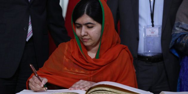 Malala Yousafzai signs a guest book at Parliament Hill in Ottawa.