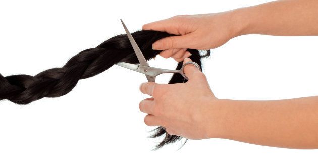 Hairdresser cutting young woman with long black hair