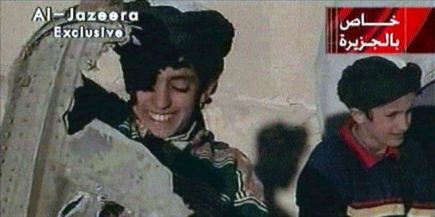 Picture taken from undated Al Jazeera television footage purportedly shows Hamza bin Osama bin Laden (L), one of the sons of Saudi-born dissident Osama bin Laden, displaying what the Taliban say is wreckage from a U.S. helicopter near Ghazni. Child at right is unidentified. [ U.S. B-52 bombers continued to pound the front line of Taliban forces north of the Afghan capital November 7, 2001. ] POOR QUALITY VIDEO DOCUMENT (CREDIT REUTERS/Al-Jazeera TV)