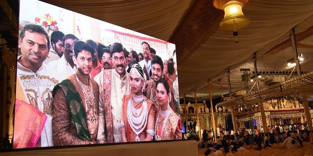 Indian mining tycoon, Gali Janardhan Reddy, (C) is seen on a big screen as he poses with his daughter Bramhani (2R) and son-in-law, Rajeev Reddy (2L) during their wedding at the Bangalore Palace Grounds in Bangalore.