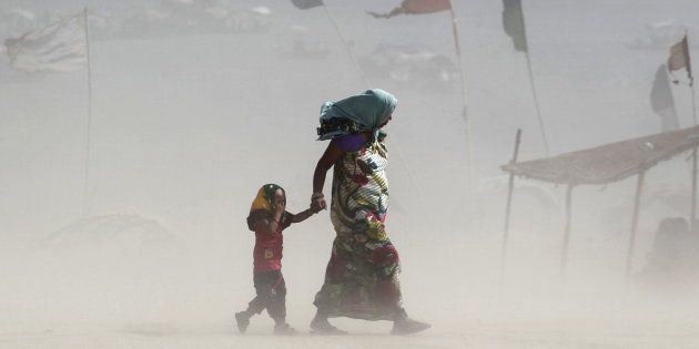 FILE PHOTO: A girl covers her eyes as she walks with her mother on the banks of the Ganges river during a dust storm on a hot summer day in Allahabad, India.