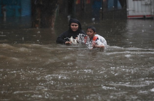 Indian people wade along a flooded street during heavy rain in Mumbai, India on August 29, 2017.