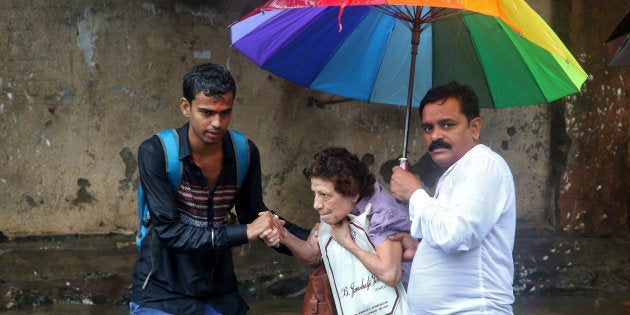 A woman is helped to move through a water-logged road after rains in Mumbai.