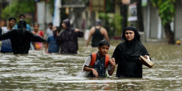An Indian woman wades with her son through flooded street during heavy rain showers in Mumbai.