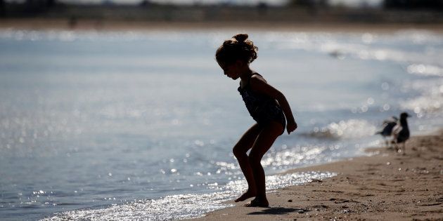 A girl is seen in silhouette by the water.