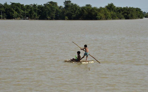 Indian children uses a raft to travel over flood waters in Araria in Bihar state on August 19, 2017.