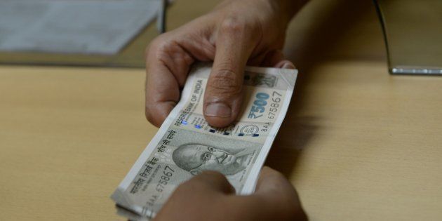 A bank staff member hands Indian 500 rupee notes to a customer on November 24, 2016, in the wake of the demonetisation of old 500 and 1000 rupee notes in Mumbai.