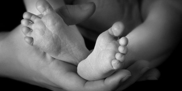 Parent's hands holding baby's bare feet