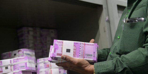 An Indian bank employee checks stacks of new 2000 rupee notes in Ahmedabad.