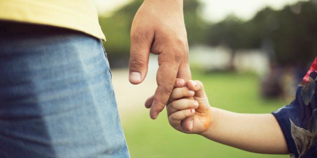 Father holding hands of his little daughter at park