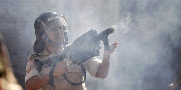 An Indian police officer fires tear gas towards protesters during a protest march in Srinagar.