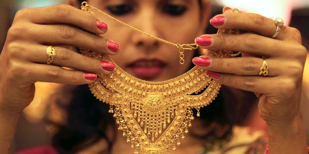 A salesgirl shows a gold necklace to customers at a jewellery showroom in the northern Indian city of Chandigarh November 11, 2012.