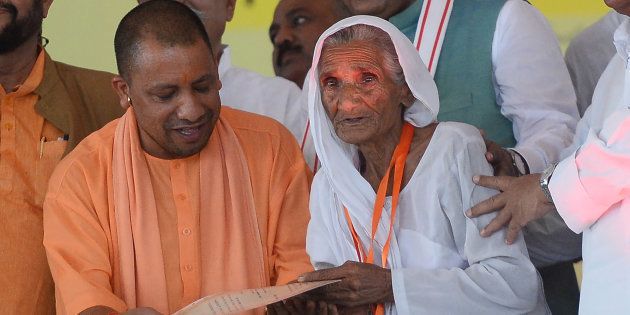 The Chief Minister of Uttar Pradesh Yogi Adityanath (L) gives a certificate to a farmer to clear her loans under the Uttar Pradesh government Fasal Rin Mochan Yojana (Farm Loan Waiver Scheme) in Allahabad on September 6, 2017.