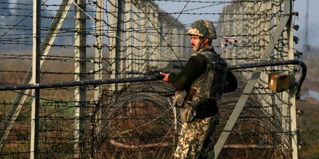 An Indian Border Security Force soldier patrols near the fenced border with Pakistan in Suchetgarh, southwest of Jammu.