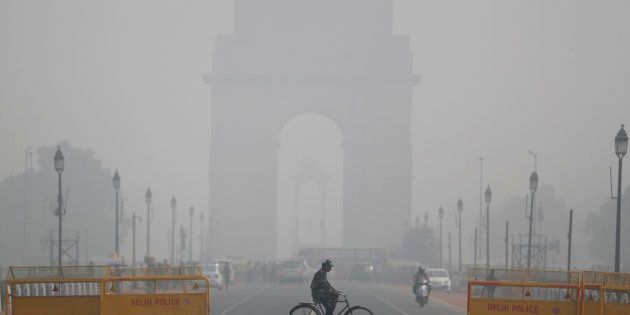 An Indian soldier rides a bicycle as past the India Gate monument on a fog enveloped morning in New Delhi, India, Thursday, Dec. 1, 2016. A thick blanket of fog engulfed Delhi, the national capital region and much of northern India, disrupting road, rail and air traffic. (AP Photo/Altaf Qadri)