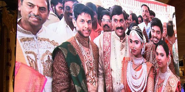 Indian mining tycoon, Gali Janardhan Reddy, (C) is seen on a big screen as he poses with his daughter Bramhani (2R) and son-in-law.