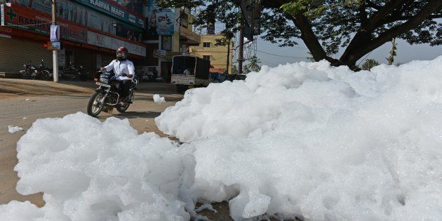 An Indian motorcyclist negotiates away from fluffy piles of foam at Varthur Kodi junction in east Bangalore.